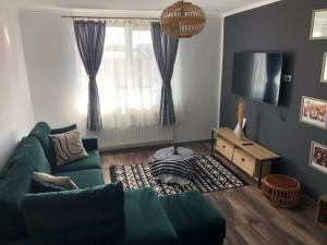 a living room with a green couch and a television at Cityscape Comfort with key lockbox in Sfântu-Gheorghe