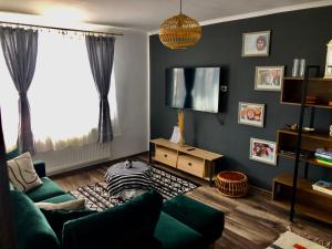 a living room with a green couch and a tv at Cityscape Comfort with key lockbox in Sfântu-Gheorghe