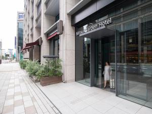 a woman walking outside of a modern hotel at Mitsui Garden Hotel Nihonbashi Premier in Tokyo