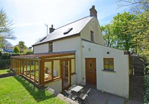 een klein wit huis met veel ramen bij Chestnut Cottage in Manorbier