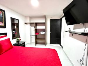 um quarto com uma cama vermelha e uma televisão de ecrã plano em Edificio Victory Medellin - Apartamentos Acogedores y Equipados 100MB Wi-Fi, Central & Terraza Compartida em Medellín