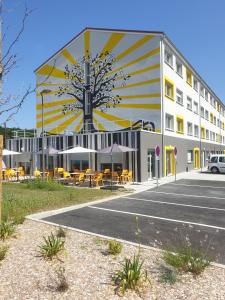 ein Gebäude mit einem Parkplatz davor in der Unterkunft Résidence Hôtelière Le Prado in Libourne