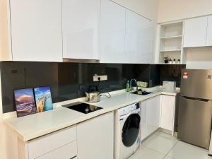 cocina con armarios blancos y lavadora en Elysia Park Residence Medini Homestay Legoland Gleneagles Johor en Nusajaya