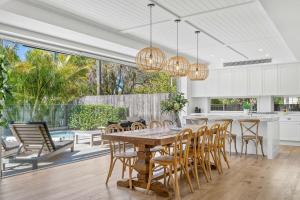 a kitchen and dining room with a wooden table and chairs at Orana Byron in Byron Bay