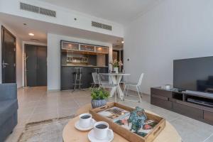 a living room with a couch and a table and a tv at Charming 1 Bedroom - Close to Metro in Dubai