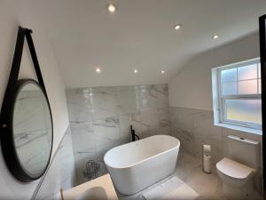La salle de bains est pourvue d'une baignoire blanche et d'un miroir. dans l'établissement Formby house, à Formby