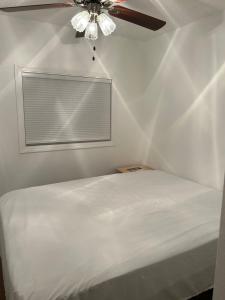 Cama blanca en habitación con ventilador de techo en Guest House Casa De Thousand Oaks, en Thousand Oaks