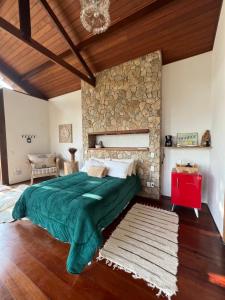 a bedroom with a large bed and a stone wall at Zatara's Lodge - Monte Verde MG in Camanducaia