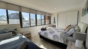 ein Schlafzimmer mit einem Bett, einem Sofa und Fenstern in der Unterkunft Tidal Dreams - Unit 3 At Sussex Inlet Retreat in Sussex inlet