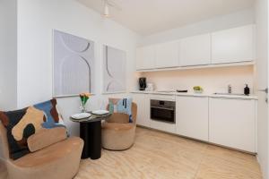 a kitchen with white cabinets and a table and chairs at Stylish studio in modern design - Tartaczna 2 by Rent like home in Gdańsk