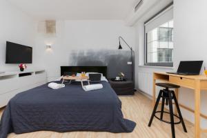 a bedroom with a bed and a desk with a laptop at Stylish studio in modern design - Tartaczna 2 by Rent like home in Gdańsk