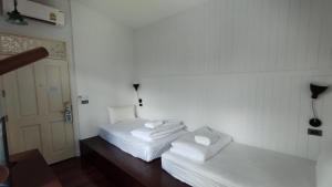 two white beds in a room with a door at Lana Beds & Space in Chiang Mai