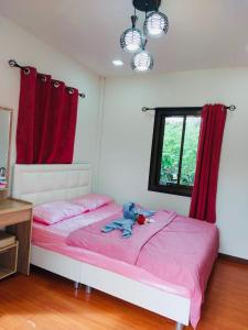 a bedroom with a bed with pink sheets and red curtains at บ้านพักตากอากาศ ยินดีต้อนรับสัตว์เลี้ยง 