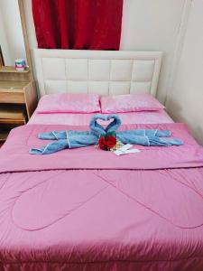 a pink bed with a pair of gloves and a bow at บ้านพักตากอากาศ ยินดีต้อนรับสัตว์เลี้ยง 