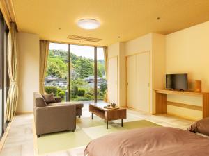 um quarto com uma cama, um sofá e uma televisão em Yukai Resort Premium Saiki Bekkan em Misasa