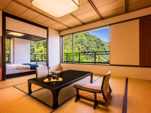 a living room with a table and a large window at Yukai Resort Premium Saiki Bekkan in Misasa
