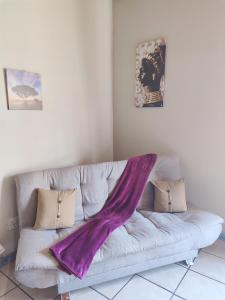 eine Couch mit einer lila Decke darüber in der Unterkunft Zulia home in Pretoria