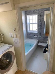 a bathroom with a tub and a washing machine at 清潔感抜群アメリカンハウス/ポーラーリゾート西軽井沢2 in Oiwake