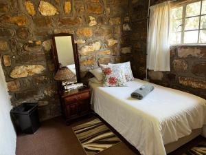 um quarto com uma cama numa parede de pedra em Echo Valley Guest Farm em Breyten