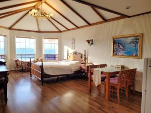 a bedroom with a bed and a desk and a table at Sunset Jeju in Jeju