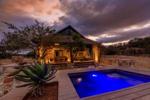 a house with a blue pool in front of a house at Zulu Rock Lodge - Babanango Game Reserve in Ulundi