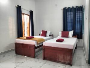 two twin beds in a room with a window at KOVIL home's Guest land in Cochin