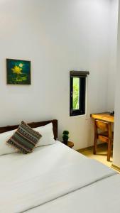 1 dormitorio con cama blanca y mesa de madera en Romo Homestay en Quang Ngai