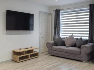 uma sala de estar com um sofá e uma televisão de ecrã plano em The Old Blue Shop em Milford Haven