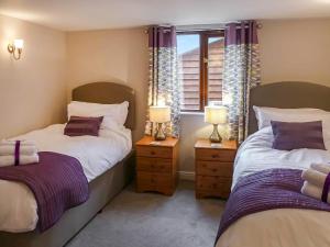 two beds in a room with two lamps and a window at Pippins in Penybont