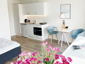 een kleine witte keuken met een tafel en stoelen bij athome apartments in Aarhus