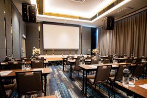 a conference room with tables and chairs and a projection screen at Frame Hotel Bangkok in Bangkok