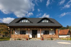 ein Haus mit einem schwarzen Dach und einer Veranda in der Unterkunft Old Cottage in Bran