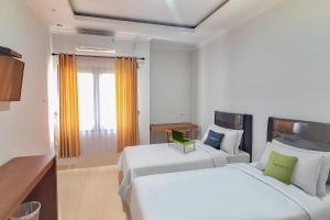um quarto de hotel com duas camas e uma janela em Urbanview Syariah Wisma Annisa Palangkaraya by RedDoorz em Palangkaraya