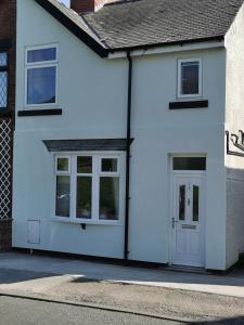 uma casa branca com portas e janelas brancas em A Bird House em Belper