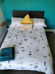 a bed with a white comforter with a blue wall at A Bird House in Belper