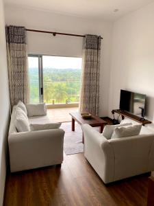 uma sala de estar com dois sofás brancos e uma grande janela em Golfers' Paradise Kahathuduwa em Gonapola