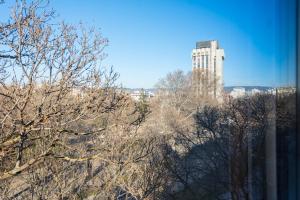 un edificio alto en la distancia con árboles en el primer plano en Студио в близост до Община Варна, en Varna