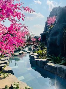 einen Fluss mit rosa Blumen im Garten in der Unterkunft Sun Villa Thanh Liên Wyndham Vườn Vua Resort & Villas in Ðồng Phú