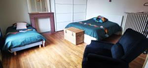 a living room with two beds and a chair at Chez Sandrine - Chambres avec pension ou demi pension in Gray-la-Ville