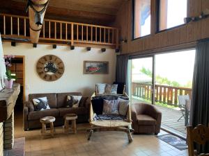 a living room with a couch and chairs and a balcony at Chalet Le Remarquable, Crest Voland in Crest-Voland