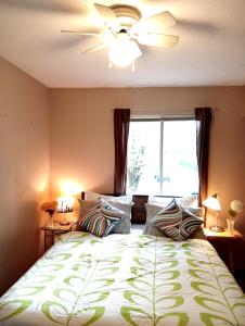 1 dormitorio con cama con almohadas y ventilador de techo en Beautiful Comfy & Relaxed Basement Room - Great Location C4 en Surrey