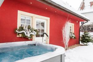 un bain à remous dans la neige en face d'une maison rouge dans l'établissement Doller Villa 4 stars Hot Tub Mountain Ski Ballon d'Alsace, à Sewen