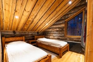 two beds in a log cabin bedroom with a window at Kelomattila in Levi