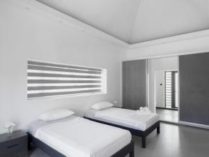 Camera bianca con 2 letti e finestra di Résidence Mo'Villa - Spacious 4 Bedrooms Villa with infinity pool a Grand Baie
