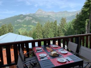 a table on a balcony with a view of mountains at Chalet Le Remarquable, Crest Voland in Crest-Voland