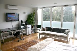 a living room with a couch and a tv at Studio for 3 with a private balcony in a Cubic house with outside pool in London