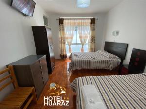 塔克納的住宿－HOTEL HUARAZ，一间卧室设有两张床、一个梳妆台和窗户。