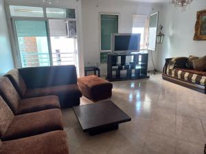 a living room with a couch and a tv at Appartement Familia Corniche Malabata Tanger in Tangier