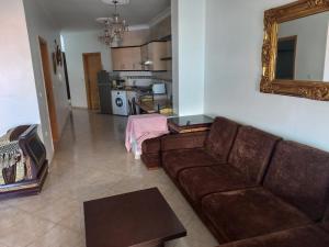 a living room with a brown couch and a mirror at Appartement Familia Corniche Malabata Tanger in Tangier