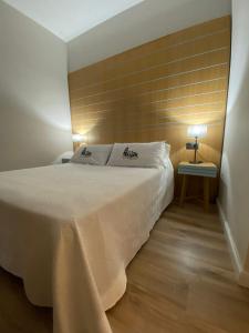 a bedroom with a white bed with a wooden wall at La Posada de San Miguel in Andújar
